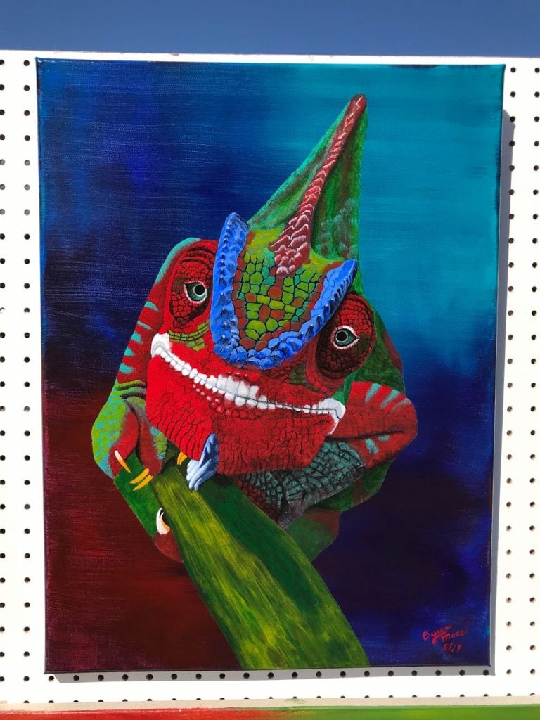 vivid, colorful painting of a panther chameleon in red, blue, and green with a blue gradient background