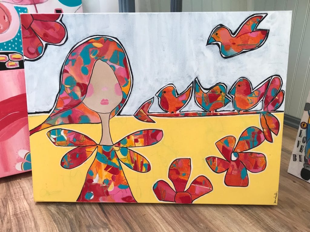 Mixed media artwork, a person with medium length hair and pink lips stands to the left next to a group of small birds and flowers, each object has varied patterns and colors on it
