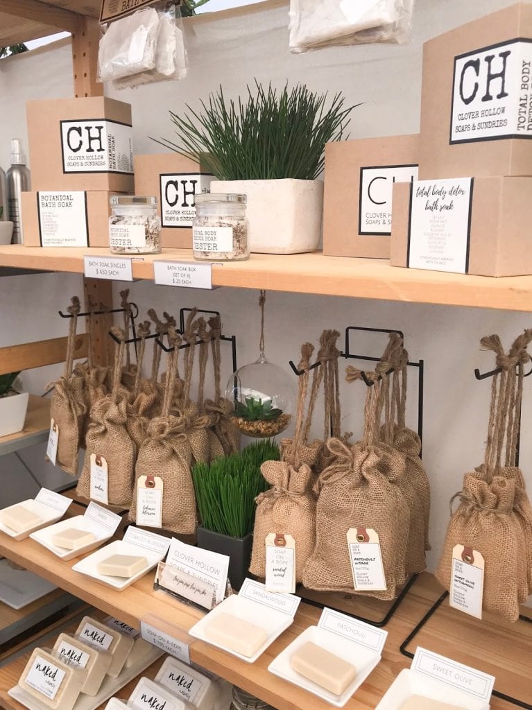 Shelves of bath products packaged in burlap bags hanging from twine. Kraft boxes can be seen above.