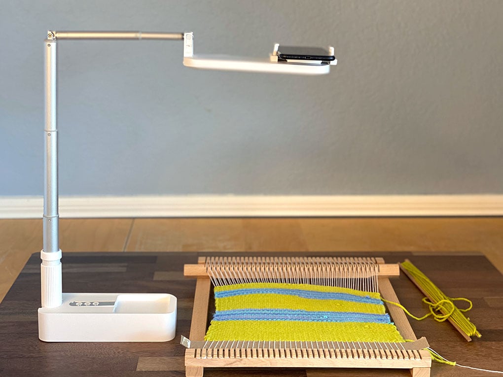 Olivia Phone Stand is perched on top of a loom in the middle of a weaving project