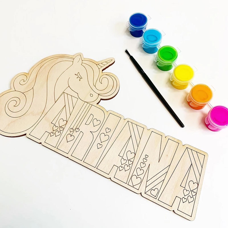 Customized Name Painting Kit by Bits of Decor shows the name "Ariana" next to a unicorn, all carved in wood with a set of paints. 