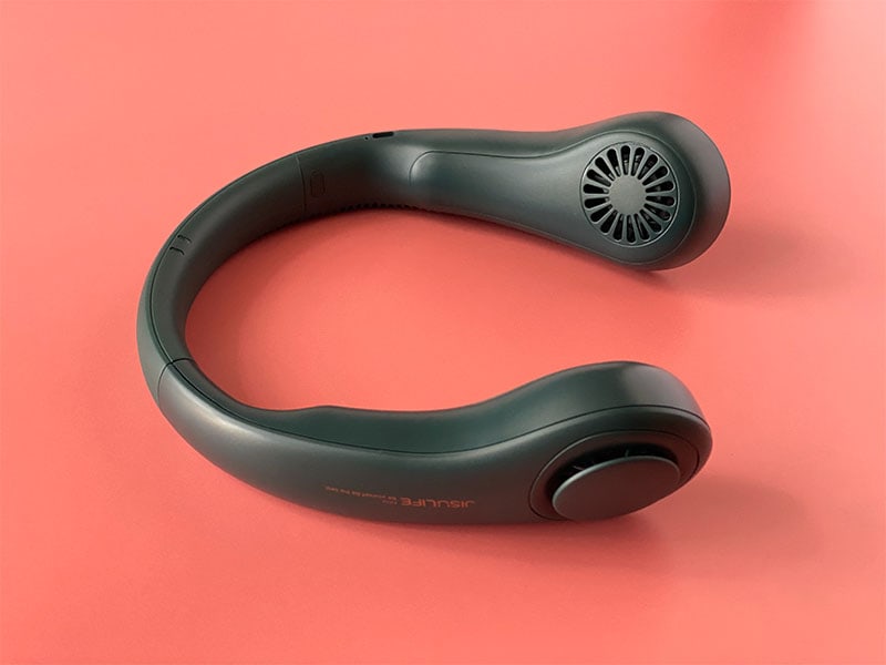 black neck fan rests on a bright coral background