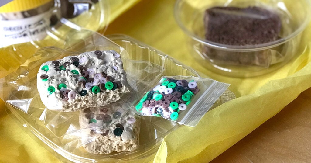 Slime rice krispie treats are packaged in plastic and sit next to a bag of extra slime mix-ins