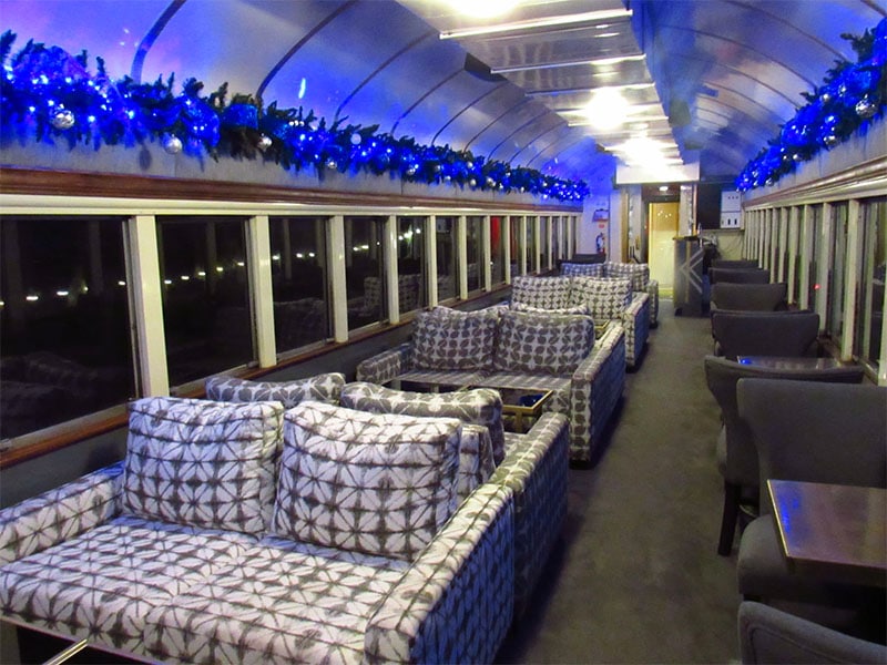 Inside the Texas State Railroad at Palestine during the Polar Express Rides shows several comfy couches and Christmas lights hung around the coach.