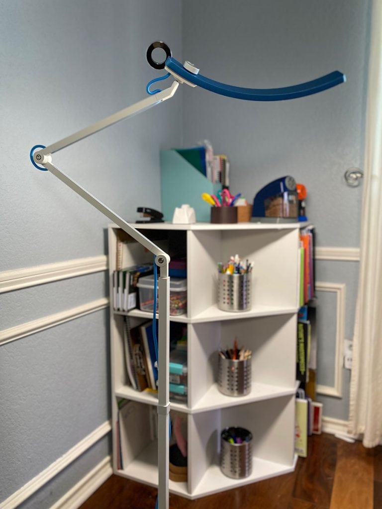 The blue BenQ e-Reading Floor Lamp is shown in full size next to a small corner bookshelf