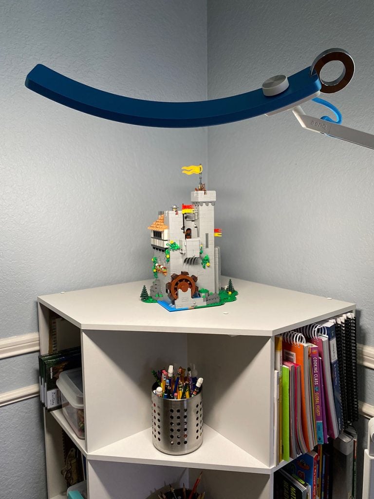 BenQ e-reading floor lamp illuminates a lego castle on a corner bookshelf